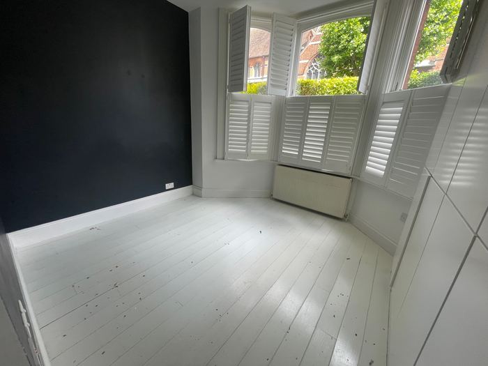 Empty bedroom before home staging, navy accent wall and bay window shutters