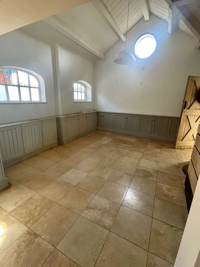 Empty vaulted living space before home staging, exposed beams and arched windows