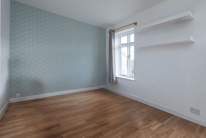 Empty bedroom before home staging, soft blue patterned wallpaper and built-in shelving