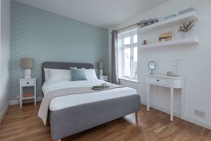 Bedroom after home staging with a grey upholstered bed and dressing table