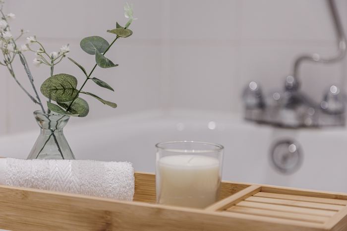 Bath caddy styling detail with a towel, candle and eucalyptus stems