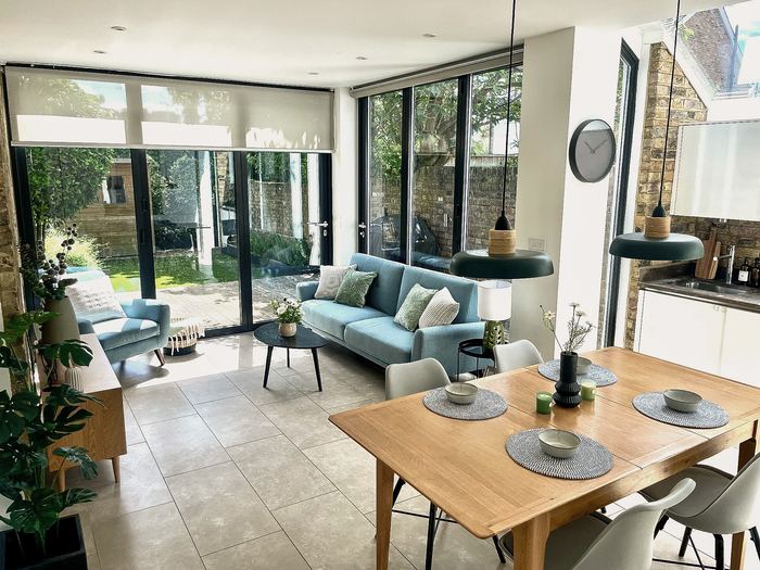 Kitchen and dining space staged for sale with a blue sofa, dining table and pendant lights