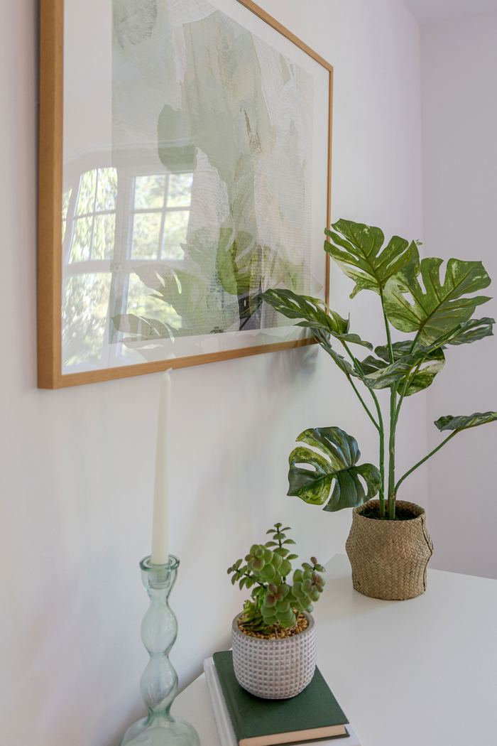 Styled shelf home organising detail with framed art, plant and candle