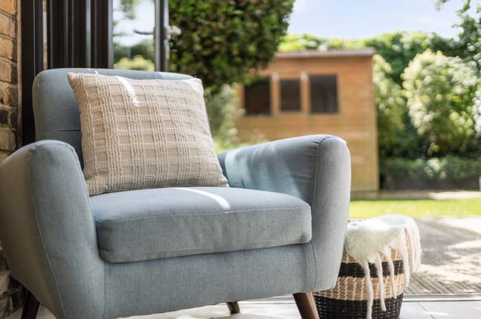 Armchair styling detail with a textured cushion and a garden view