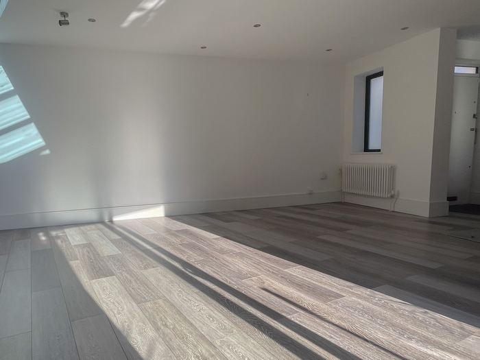 Empty open-plan living space before home staging, grey tiled flooring