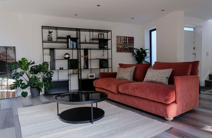Living space staged with a rust velvet sofa and gallery wall, styling to sell