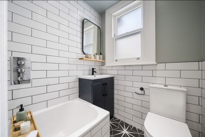 Bathroom styled with white subway tiles, a black-framed mirror and patterned floor tiles