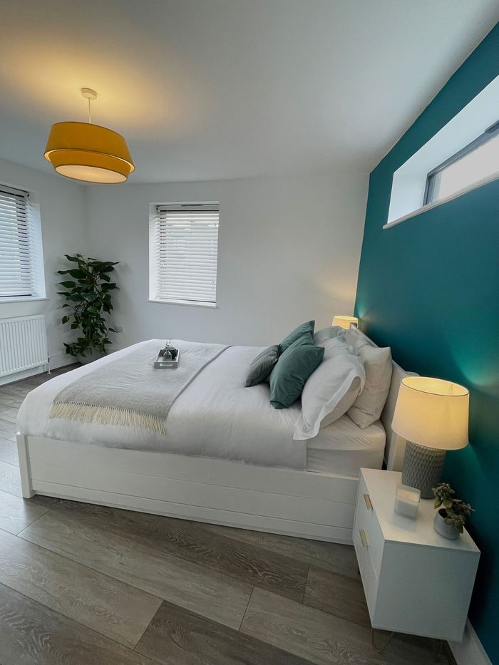 Bedroom staged with a teal accent wall and yellow pendant light, home stylist project
