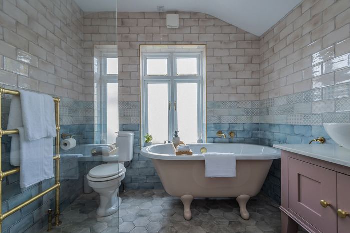 Bathroom styled with a blush roll-top bath and patterned tiling