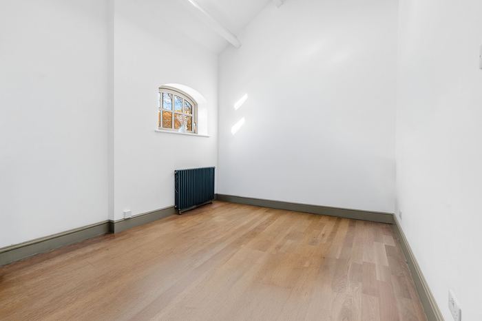Empty vaulted bedroom before home staging, arched window