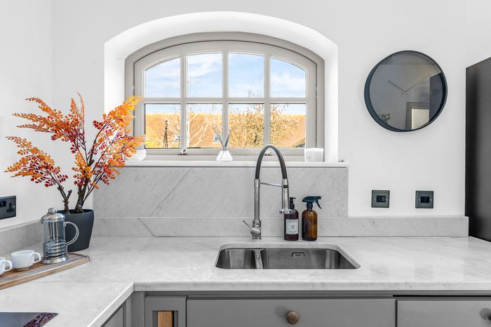 Kitchen counter styling detail beneath an arched window