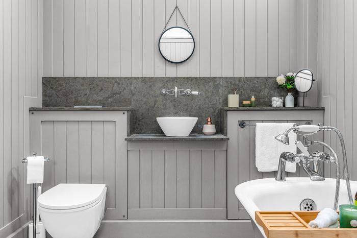 Bathroom styled with grey panelling, a round mirror and vessel sink