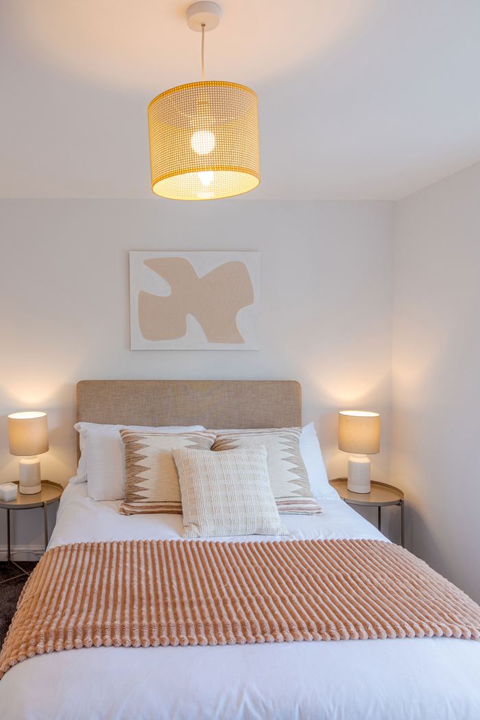 Bedroom staged with a tan headboard and patterned artwork, interior styling