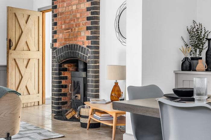 Living room styling detail with a wood-burning stove and brick chimney breast