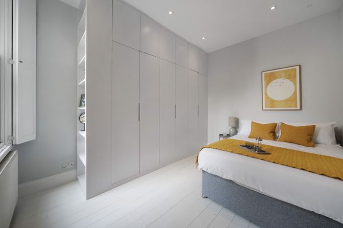 Bedroom styled with built-in wardrobes and ochre-toned accents