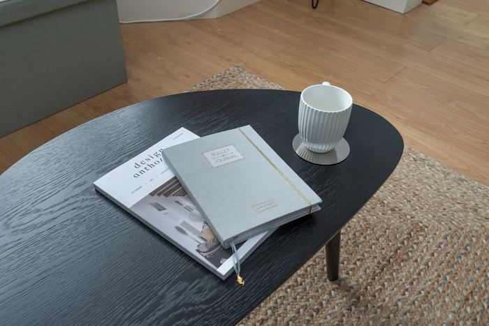 Coffee table home organising detail with books, a journal and mug
