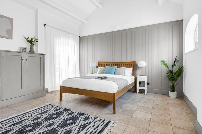 Bedroom staged with panelled walls, wood bed frame and palm plant
